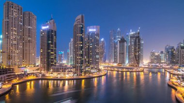 Dubai Marina gezinti güvertesi ve kanalı, gün batımından sonra Dubai, BAE 'de yüzen yat ve teknelerle hava görüntüsü. Modern kuleler ve trafik