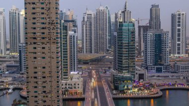 Dubai, Birleşik Arap Emirlikleri güneş battıktan sonra gece geçiş timelapse Dubai Yat Limanı mesire ve kanal kayan yat ve tekne ile günler hava üstten görünüm. Modern kuleleri ve Köprüde trafik