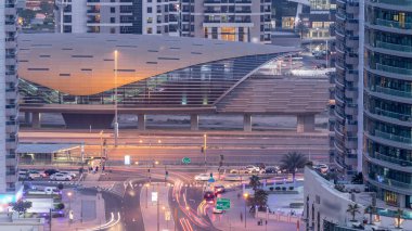 Dubai, BAE 'de gün batımından sonra metro istasyonu yakınlarındaki Dubai Marina yol kavşağının hava görüntüsü gece gündüz geçiş zamanı. Modern kuleler ve trafik