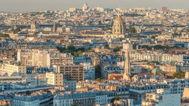 Paris 'teki evlerin çatılarının üstündeki hava manzarası. Günbatımından önce altın kubbe ve uzun gölgelerle akşam manzarası