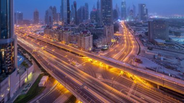 Dubai şehir merkezi, gece gündüz UAE karayolu trafiği ile hava değişimi. Al Saada caddesinin kavşağı ve finans merkezi yolu yakınında modern kuleleri olan gökdelenin çatısı manzaralı.