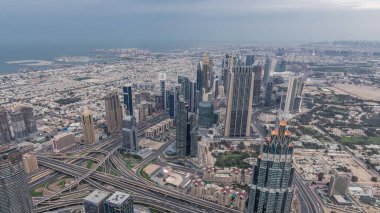 Dubai'de şehir merkezi ve finans bölgesi gece saati. Bulutlu gökyüzü ve karayolu üzerinde trafik. Burç Halife bakış açısından kuleler ve gökdelenler ile havadan görünüm.