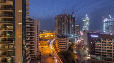 Gün batımından sonra Dubai Marina 'da gökdelenler ve hava yürüyüşü gününden geceye geçiş zamanı. Yol trafiği olan modern kuleler ve tekneler. Birleşik Arap Emirlikleri