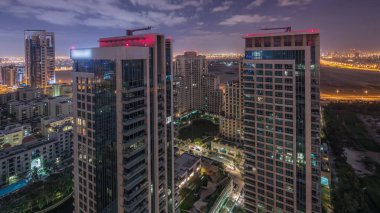 Tüm gece boyunca yeşilliklerin hava manzarası tepeden görünüyor. Aydınlatılmış ofis ve golf sahasının yukarısından binalar.