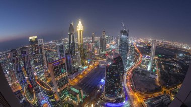 Sheikh Zayed Yolu yakınlarındaki binaların silueti ve Dubai, BAE 'deki hava gününden geceye geçiş. Günbatımından sonra finans merkezinde ve şehir merkezinde park yeri olan modern kuleler ve gökdelenler.