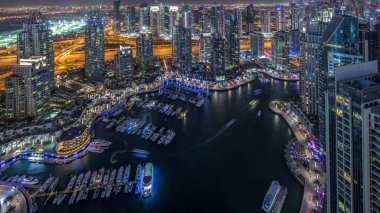Dubai Marina gökdelenleri ve Jumeirah göl kuleleri Birleşik Arap Emirlikleri 'nde hava gününden geceye geçiş zamanlarını gösteriyor. Yolda trafik ve yüzen yatlar.