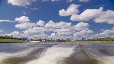 Astana, Kazakistan. Keyif teknesinden Astana 'da Ishim nehrinde hareketli bir seyahat görüntüsü. Mavi gökyüzü ve bulutlarla dolu bir yaz gününde. Bulanık hareket