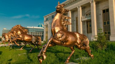 Gün batımında Astana Opera Tiyatrosu 'nun önündeki yeşil çimlerde atların güzel heykelleri zaman aşımına uğrar. Nur-Sultan şehri