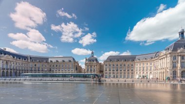 Place de la Bourse ve Miroir d 'eau hiperlapse Bordeaux, Fransa' da, tarihi mimariyi yansıtıyor. Turistler şehir simgesi ve çeşmenin tadını çıkarıyorlar. Trafik ve tramvay zamanı geçiyor..