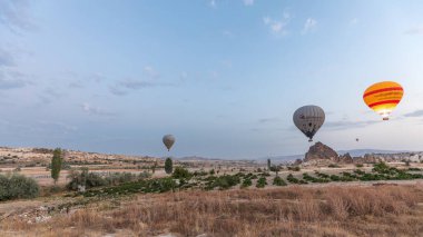 Türkiye 'nin Kapadokya kentindeki alışılmadık kayalık zaman dilimi üzerinde güzel renkli sıcak hava balonları havalanıyor ve açık bir sabah gökyüzünde uçuyor.