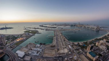 Palm Jumeirah Adası gün gece geçiş timelapse için hava gün batımı manzarası. Üstten görünüm ışıklı Villaları, otelleri ve yatlar ile akşam. Yeni cruise terminal inşaat süreci