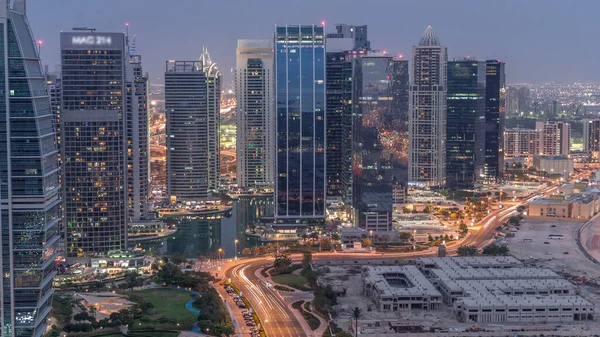 Jumeirah Lake Towers yerleşim bölgesi Dubai Marina yakınında gece geçiş timelapse gün havadan. Işıklı modern gökdelenler ve yukarıdan park