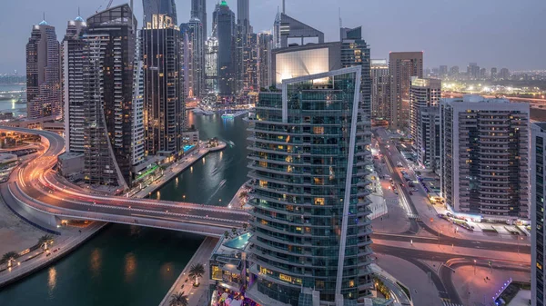 Gün batımından sonra Dubai Marina konutlarının ve ofis gökdelenlerinin havadan panoramik görüntüsü. Rıhtımdan geceye geçiş zamanı ve trafik. Yüzen tekneler ve yatlar