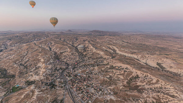 Aerial view from hot air balloon timelapse hyperlapse with other flying balloons during Sunrise over the fairytale landscape hills of Kapadokya. Goreme, Cappadocia, Turkey