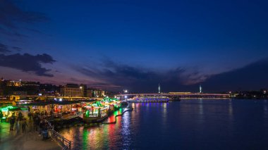İstanbul 'un İstanbul silueti, gün batımından sonra İstanbul' da, İstanbul Boğazı 'ndaki Golden Horn' da tekne istasyonu yakınlarındaki yolcu feribotları. Arka plandaki cami ve köprü bahar günündeki su yansıması ile