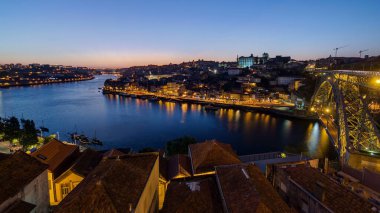 Panorama old city Porto at river Duoro, with Port transporting boats day to night transition timelapse with the Arrabida bridge after sunset, Oporto, Portugal