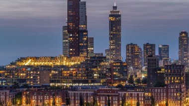 Rotterdam, Hollanda 'daki Katendrecht yarımadası ve Maashaven limanının hava ve gece geçiş zamanı. Şehir silueti modern gökdelenler ve geleneksel Hollanda rıhtım evleri