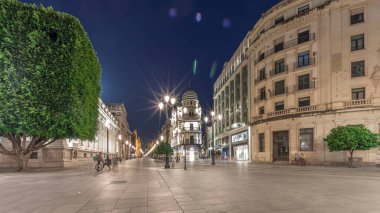 Avenida de la Constitucion, Seville, İspanya 'da günden geceye zaman dilimi. Modern sokak lambaları, yayalar ve kentsel atmosferi olan tarihi mimari. Iconic Adriatica binası gün batımından sonra parlıyor.