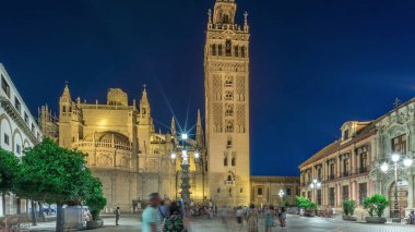 La Giralda ve Seville Katedrali günden geceye geçiş zamanı, gün batımından sonra altın ışıklarla parıldıyor. Tarihi çan kulesi, gotik detaylar ve Seville, İspanya 'da aydınlatılmış sokaklar.