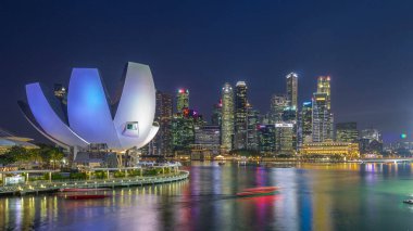 Futuristic architecture flower shape design of the Art Science museum day to night transition timelapse after sunset. Skyscrapers skyline city of Singapore.