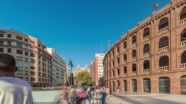 Panorama, Nord istasyonu yakınlarındaki Bullring of Valencia (Plaza de Bous) zaman ayarlı boğa güreşi müzesini gösteriyor. İnsanlar tarihi amfi tiyatronun etrafında mavi bir arkaplanla dolaşıyorlar. Valencia, İspanya.