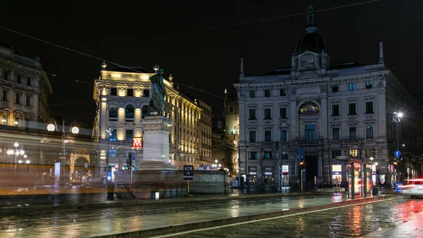 Cordusio Meydanı ve Dante Caddesi çevresindeki saraylar, evler ve binalar İtalyan moda ve lüks başkentinde gece panoramik. Yazar ve şair Giuseppe Parini anıtı. Tramvaylar geçiyor.