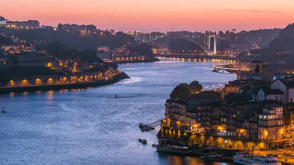 Day to night transition aerial view of the historic city of Porto, Portugal panoramic timelapse from the Dom Luiz bridge. Illuminated waterfront and curved river from above
