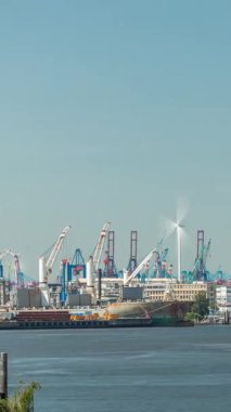 Hamburg kargo limanının zaman çizelgesi Elbe Nehri 'nde konteyner terminalleri, vinçler ve kargo gemileri sergileniyor. Tekneler ve gemiler modern binaların yanından geçerek dinamik bir deniz manzarası yaratıyorlar. Almanya