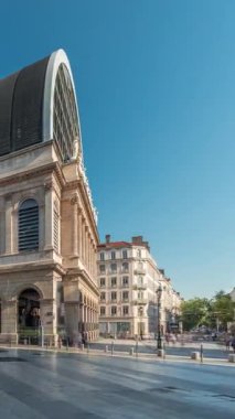 Modern cam kubbe ile birleştirilmiş neoklasik mimari içeren Lyons opera binasının hiperlapesi. Mavi gökyüzünün altında heykelleri olan tarihi ve turistik bir yer. Yan görünüm zaman dilimi