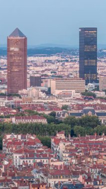 Gün batımından sonra Lyon 'un panoramik hava görüntüsü Fourviere Hill' den gece dönüşümüne kadar. Gökdelenler gökdelenlerle çevrili ve sıcak bir akşamda aydınlanan ikonik şehir simgeleri yer alıyor.