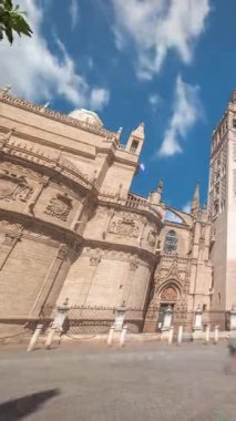 Virgen de los Reyes Meydanı, Seville Katedrali ve Giralda Kulesi zaman atlamalı Seville, İspanya 'da. Dünyanın en büyük gotik katedrali, mavi bulutlu gökyüzünün altındaki UNESCO miras alanı.