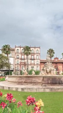 Sevilla 'daki Hispalis Çeşmesi, en güzel çeşmelerden biri, renkli çiçekler ve tarihi binalarla çevrili. Arka planda bulutlu bir gökyüzü ile hızlandırılmış zaman çizelgesi.
