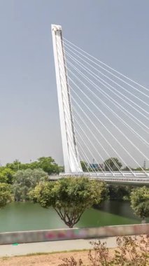İspanya 'nın Sevilla kentindeki Guadalquivir Nehri' nin üzerinden geçen uzun kolon ve çelik kablolu Alamillo Köprüsü. Açık mavi gökyüzü altında yoğun trafik ile modern süspansiyon tasarımının hızlandırılmış zamanlaması.