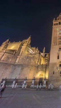 La Giralda ve Seville Katedrali geceleri aşırı hızlanarak altın ışıklarla parıldıyor. Tarihi çan kulesi, gotik detaylar ve aydınlatılmış sokaklar Sevilla, İspanya 'da büyülü bir atmosfer yaratıyor.