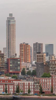 Rotterdam, Hollanda 'daki Katendrecht yarımadasının ve Maashaven limanının uçuş zamanı. Sabahları sıcak ışık, modern gökdelenler ve geleneksel Hollanda rıhtım evleri ile şehir silueti yükseliyor.
