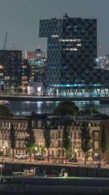 Geceleri Katendrecht yarımadasının panoramik zaman çizelgesi, Hollanda Rotterdam 'daki Maashaven limanı ve nehri. Aydınlatılmış şehir silüeti, modern gökdelenler ve geleneksel rıhtım evleri
