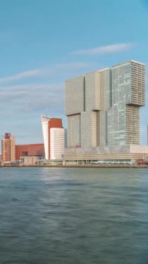 Hollanda, Rotterdam 'daki Maas Nehri' ni kapsayan Kuğu adlı Erasmus Köprüsü zaman dilimi. Hollands 'ın en büyük kablo destekli basküle köprüsü gökdelenleri, tekneleri ve bulutlu mavi bir arkaplanı var.