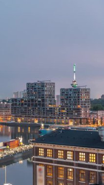 Güneş doğmadan önce Maashaven 'daki kuleler üzerindeki hava manzarası demirli gemilerle, Katendrecht ve Maas Nehri' yle, Rotterdam 'la geçiş zamanlarını gösteriyor. Aydınlatılmış fabrika ofis ve olay alanına dönüştürüldü
