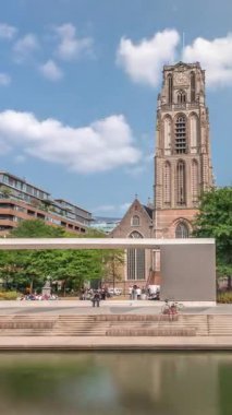 Laurenskerk Saint Lawrence Kilisesi, Rotterdam Grotekerkplein 'da. İnsanlar mavi bulutlu gökyüzünün altında çimlerde dinleniyorlar. Kanal merdivenlerinin yanında saati olan tarihi çan kulesi. Hollanda