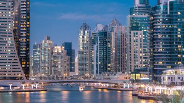 Dubai Marina rıhtımı, Dubai 'deki köprüden gece vardiyasına kadar uzanan kuleleri ve yatları olan Birleşik Arap Emirlikleri. Çevresinde yapay kanallar ve aydınlık gökdelenler olan bir bölge.