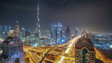 Modern gökdelenler ve yoğun gece otoyolları Dubai şehir merkezindeki lüks geçiş zamanlarında. Kule çatısından üst hava manzarası. Yol kavşağı trafiği. Dubai, Birleşik Arap Emirlikleri