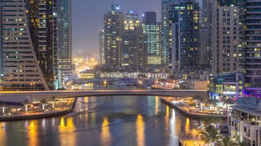 Dubai, BAE 'de gün batımından sonra yüzen yat ve teknelerle Dubai Marina gezinti güvertesi ve kanallarının havadan zamana güzel bir görüntüsü var. Modern kuleler ve yoldaki trafik.
