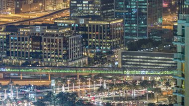 Çeşmeler en yüksek gökdelen gece timelapse, Dubai ana girişe yakın. Hava üstten görünüm yukarıdan palmiye ve trafik ile şehir merkezinde akşam aydınlatılmış Dubai'de bir daire yolda