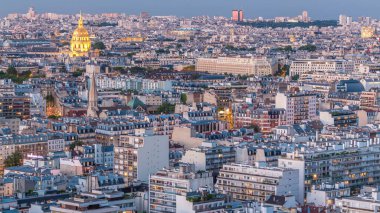 Paris 'teki evlerin çatılarının üstündeki hava panoraması gece gündüz geçiş zamanı. Günbatımından sonra aydınlanan gece manzarası, kiliseler ve diğer manzaralar.