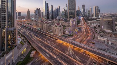 Şeyh Zayed Yolu yakınlarındaki kavşak trafiğinin Skyline görüntüsü ve Dubai, BAE 'deki gece gündüz geçiş zamanı. Finansal merkezdeki aydınlık gökdelenler şehir merkezinin yukarısından gökyüzü manzarası