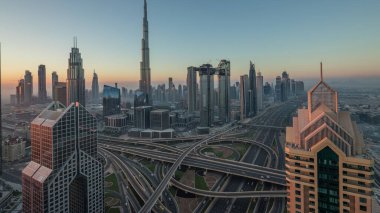 Dubai şehir merkezi silueti en yüksek gökdelenler ve karayolu kavşak gece gündüz geçiş timelapse üzerinde en işlek trafik ile. Yukarıdan havadan görünüm