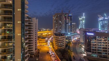 Gün batımından sonra Dubai Marina 'da gökdelenler ve hava yürüyüşü gününden geceye geçiş zamanı. Yol trafiği olan modern kuleler ve tekneler. Birleşik Arap Emirlikleri