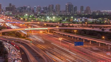 Dubai Golf Sahası 'nın arka plan hava gününden geceye geçiş zamanlarında yeşillik ve tekom bölgelerinden oluşan bir manzarası var. Şeyh zayed yolunda trafik kesişiyor.