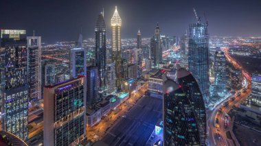 Sheikh Zayed Yolu yakınlarındaki binaların silueti ve Dubai, BAE 'deki hava gününden geceye geçiş. Günbatımından sonra finans merkezinde ve şehir merkezinde park yeri olan modern kuleler ve gökdelenler.