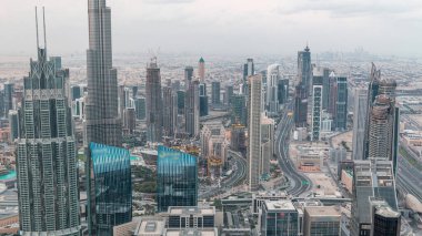 Dubai Şehir Merkezi gökdelenleri ve Burj Halife 'nin gece gündüz geçiş yaptığı fütüristik şehir manzarası. Gündoğumundan önce çatıdan modern kuleleri ve inşaatı olan sabah manzarası